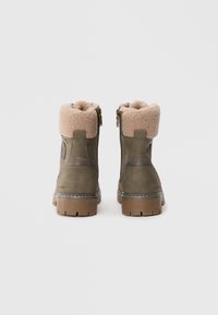 Braune und beigefarbene gefälschte Fell gefütterte Ankle-Boots mit seitlichen Reißverschlüssen, olivgrünes Wildleder, Gummisohlen mit strukturiertem Profil und kontrastierenden Steppnähten.