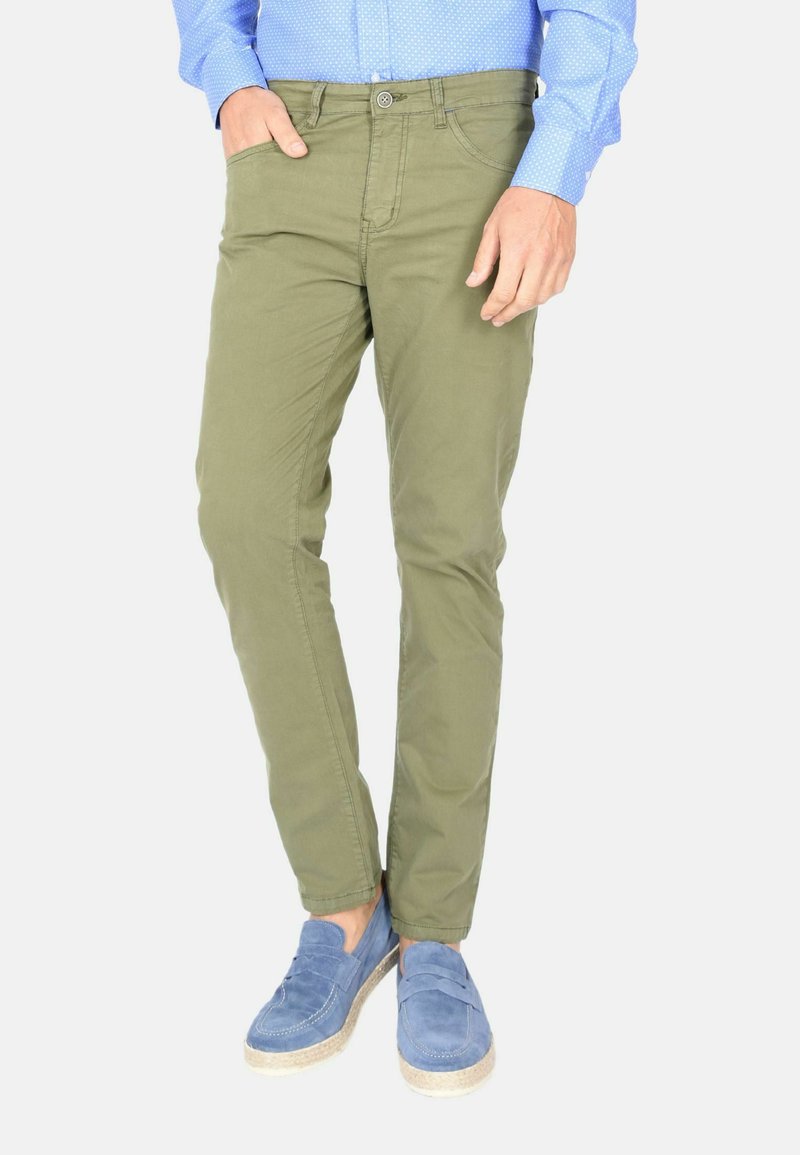 Chinos slim fit verde oliva realizzati in cotone morbido, con tasche anteriori e chiusura a un solo bottone, abbinati a mocassini in suede blu.