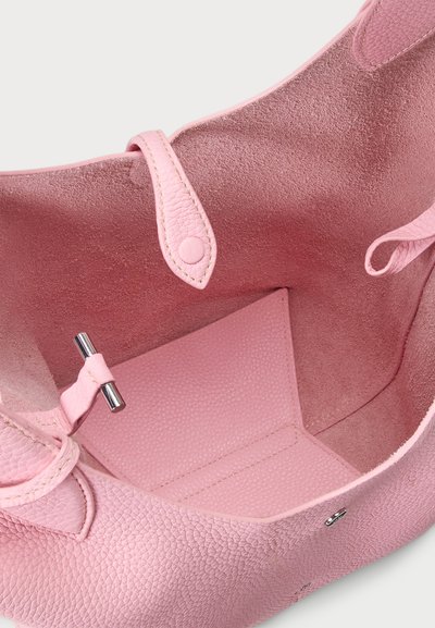 Ροζ δερμάτινη τσάντα tote με υφή στο εξωτερικό, λείο εσωτερικό, κούμπωμα με κουμπί και μικρή μεταλλική λεπτομέρεια μέσα.