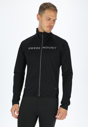 Schwarze Zip-Jacke mit langen Ärmeln und "SWEDEN MOUNT" Logo über der Brust. Hergestellt aus leichtem Material und in taillierter Passform.