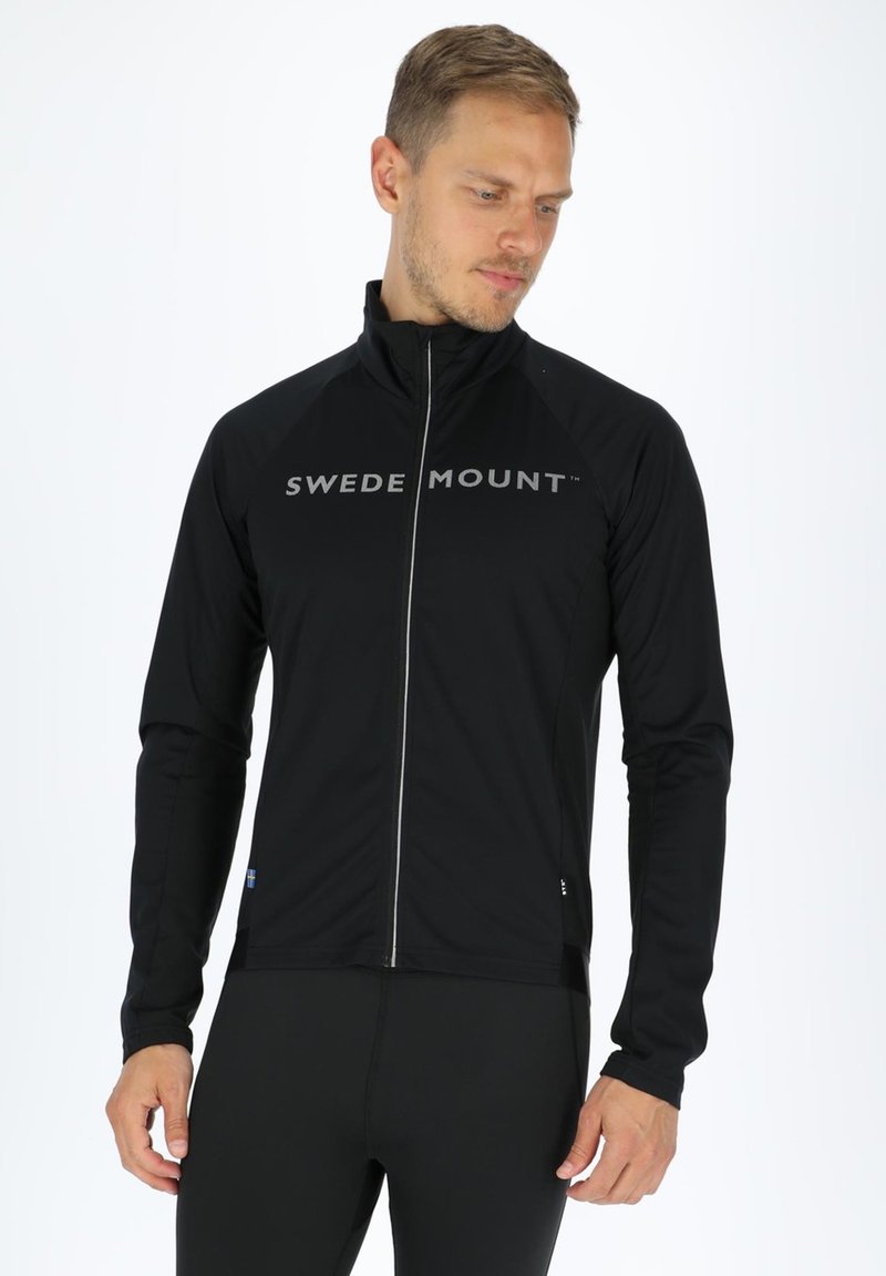 Schwarze Zip-Jacke mit langen Ärmeln und "SWEDEN MOUNT" Logo über der Brust. Hergestellt aus leichtem Material und in taillierter Passform.