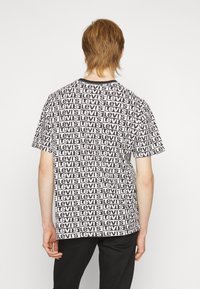 Camiseta blanca con un diseño repetido del logotipo negro de Levi's, de mangas cortas y cuello redondo, fabricada en suave material de algodón.