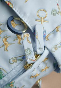 Ljusblått tyg med tryckta mönster av nycklar och djur. Inkluderar gyllene hårdvara, en marinblå ring och flikar för dragkedjor. Texturerad yta.