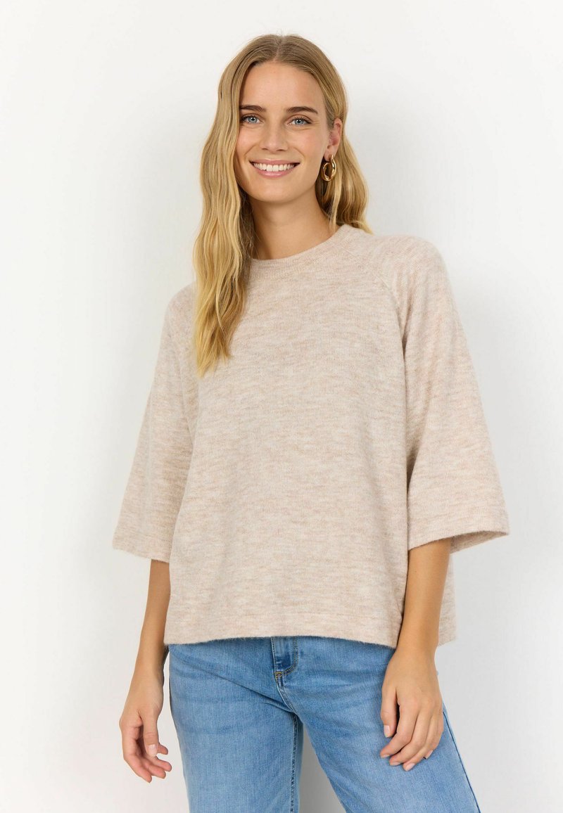 Maglione a maglia di un beige chiaro con una vestibilità comoda e maniche corte e larghe, abbinato a jeans in denim blu. Tessuto morbido, design semplice.