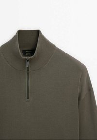 Olivgrüner Strickpullover mit hohem Kragen und halbem Reißverschluss. Verfügt über eine gerippte Textur und eng anliegende Ärmel, aus weichem Material gefertigt.