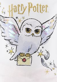 Koszulka z grafiką w stylu Harry'ego Pottera, przedstawiająca ilustrowaną białą sowę z iryzującymi skrzydłami, trzymającą list, otoczoną złotymi gwiazdami i piórami.