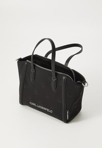 Black handbag made of textured fabric, featuring dual handles, a zip closure, and embossed logo pattern. Silver hardware accents.