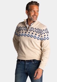 Beige pullover trui met een kwart rits, met een geometrisch blauw patroon op de borst, gemaakt van een gladde, zachte stof.