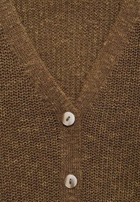 Gilet en tricot marron avec un col en V et trois grands boutons ronds. La texture est lâche et tissée, offrant un tissu respirant.