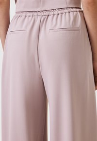 Lila wijde broek met een gladde textuur, voorzien van een elastische tailleband en twee achterzakken, zo goed als zonder versieringen.
