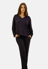 Ensemble de détente noir comprenant un haut à manches longues en col en V et un pantalon à cordon de serrage, fabriqué en matériau doux avec deux poches avant.