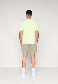 Ανοιχτό πράσινο κοντομάνικο μπλουζάκι σετ με γκρι σορτς. Το ύφασμα είναι μαλακό και η εφαρμογή άνετη. Λευκά αθλητικά παπούτσια και κάλτσες ολοκληρώνουν το σύνολο.