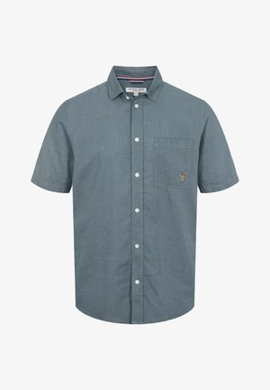 Lyhythihainen napillinen paita tummasta teal-kankaasta. Vasemmassa rinnassa oleva tasku ja pieni logotunnus. Klassinen paitakaulus.