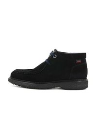 Scarpa alla caviglia nera in pelle scamosciata con lacci sulla parte anteriore, suola testurizzata e piccola etichetta sul tallone, fotografata su uno sfondo bianco.