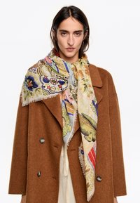 Bufanda de varios colores y con estampado, hecha de tela ligera, que presenta diseños florales y de animales, drapeada alrededor del cuello, con bordes con flecos.