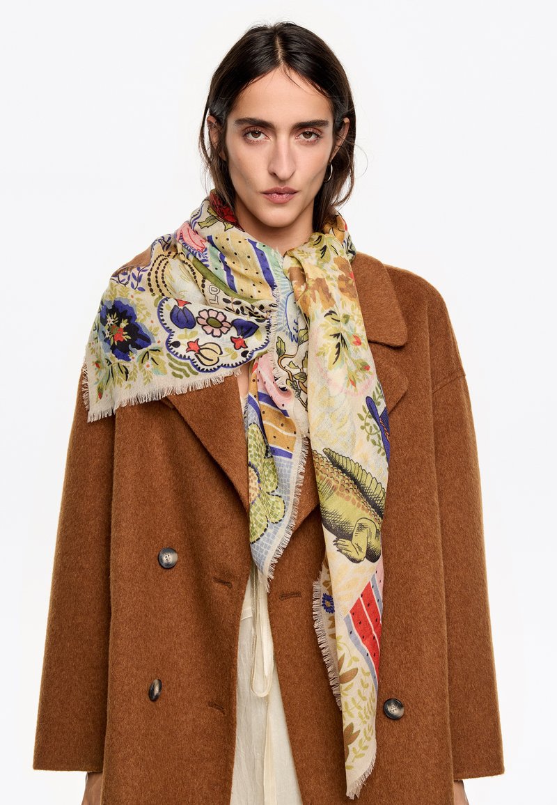 Bufanda de varios colores y con estampado, hecha de tela ligera, que presenta diseños florales y de animales, drapeada alrededor del cuello, con bordes con flecos.