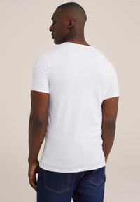 Witte t-shirt met korte mouwen, een getailleerd ontwerp, een gladde textuur en een ronde halslijn, gecombineerd met donkerblauwe spijkerbroek.