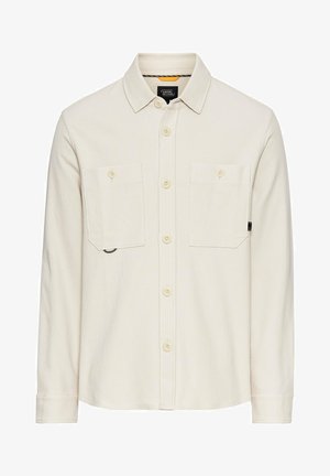 Witte lange mouwen shirt van textuurstof met twee borstzakken, knoopsluiting en een afgeronde onderkant.