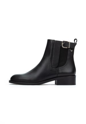Botines de cuero negro con paneles elásticos laterales, un pequeño tacón cuadrado y una hebilla metálica decorativa en el costado. Textura suave, punta afilada.