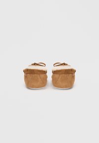 Brown suede slippers with a fluffy cream lining, round toe, and decorative ties on the rear for closure. Flat white outsole.