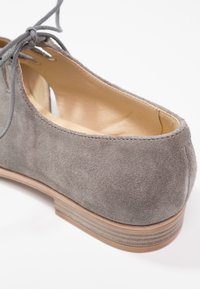 Chaussure plate à lacets en daim gris avec un petit talon empilé en bois et une doublure intérieure en cuir beige, vue de l'arrière.