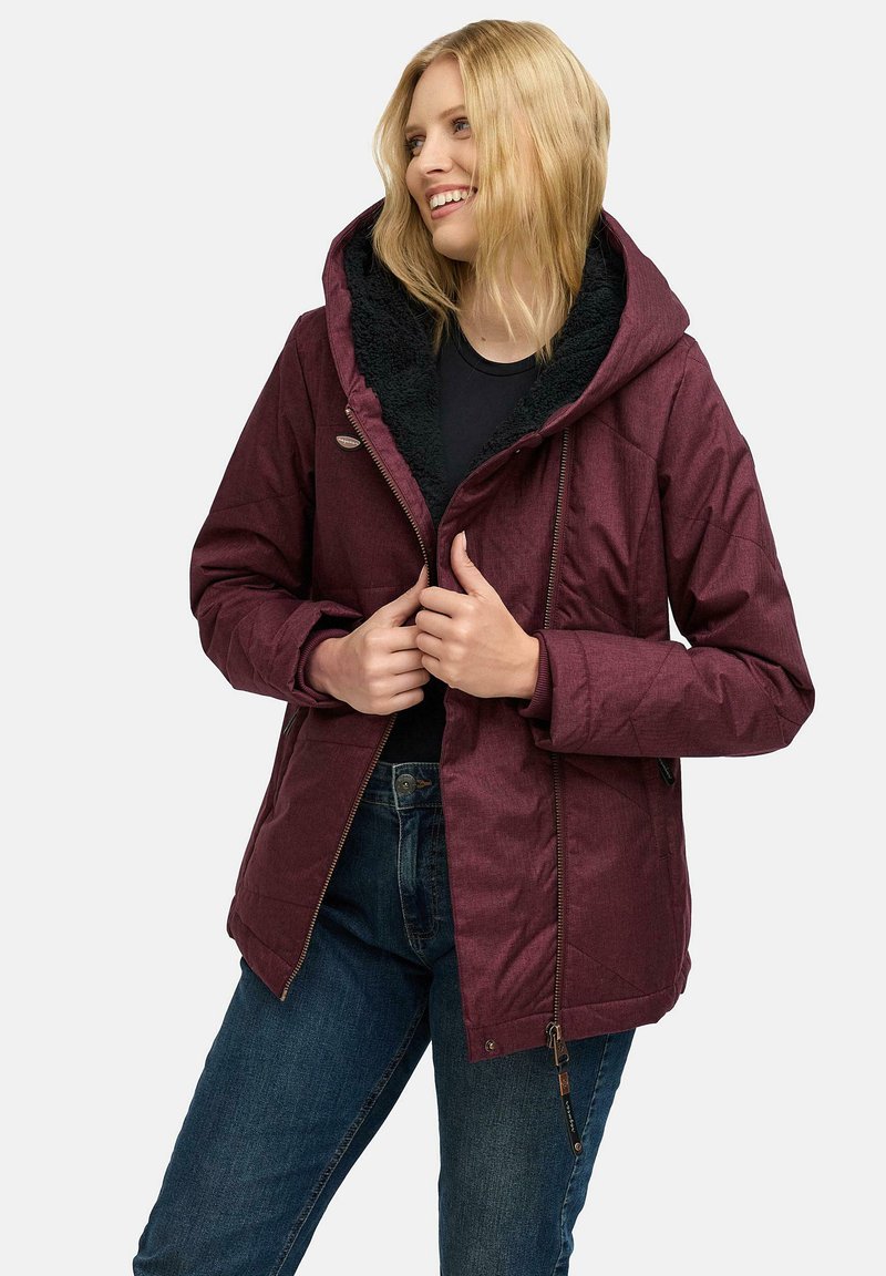 Bordowa kurtka na zamek z kapturem, z podszytym kołnierzem z polaru, pikowaną teksturą i dwoma bocznymi kieszeniami. Noszona na czarnej bluzce i dżinsach.