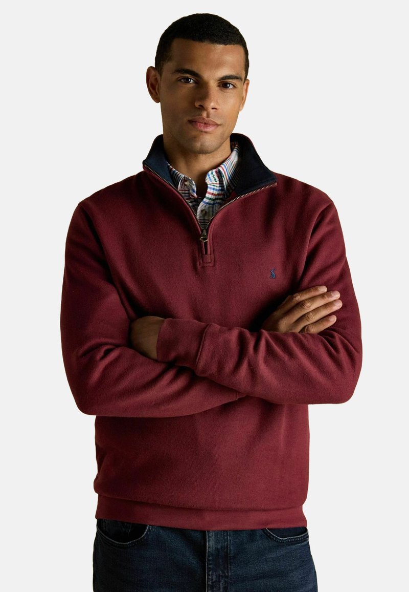 Bordeaux fleece half-zip sweater met een marineblauwe kraag, met een subtiel logo op de borst en een relaxed fit. Draagt over een geruit shirt.