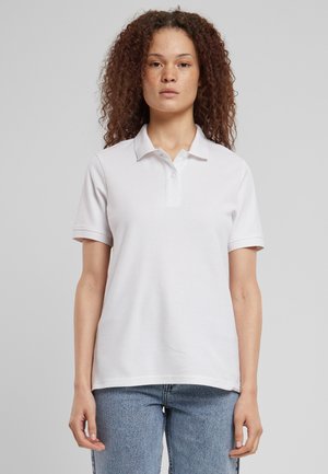 Witte polo met een kraag en drie knopen, gemaakt van gladde stof. Korte mouwen, relaxte pasvorm, gecombineerd met lichtblauwe jeans.