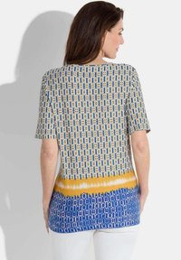 Korte mouwen top met een multicolor patroon in geel, blauw en wit. Heeft een ronde halslijn en een iets losse pasvorm.