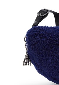 Granatowa torba z teksturowanego materiału, z czarnym regulowanym paskiem i małym metalowym charms'em w kształcie robota zwisającym z boku.