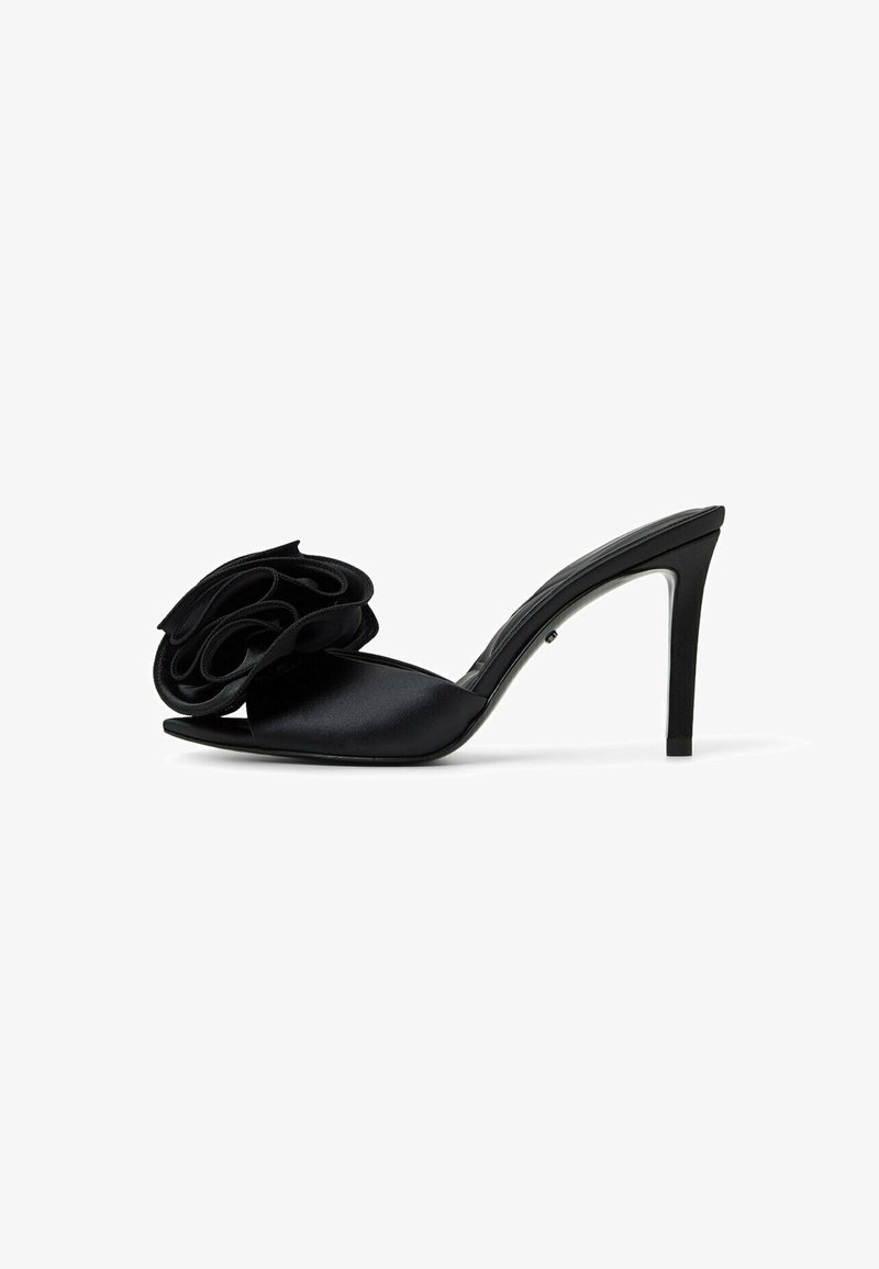 Sandalo alto in satin nero con un grande ornamento floreale sulla punta, design open-toe e sottile tacco a stiletto.