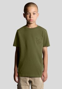 Oliven grønt bomulds T-shirt med korte ærmer og rund hals. Har et præget ørnedesign på venstre bryst. Neutral baggrund.
