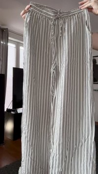 Weite Hose aus einem leichten Stoff, mit vertikalen schwarz-weißen Streifen, elastischem Bund und Kordelzug-Detail.