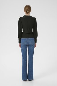 Black, long-sleeve top with a fitted waist and puffed shoulders, paired with flared blue jeans featuring back pockets and a classic denim texture.