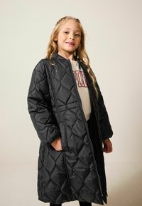 Palton negru matlasat cu fermoar frontal, mâneci lungi �și buzunare laterale. Prezentă un model în diamante și o textură ușor lucioasă.