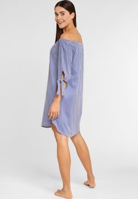 Blau-weiß gestreiftes Off-Shoulder-Kleid mit gebundenen Ärmeln, leichtem Stoff und lockerer Passform, endet oberhalb des Knies.