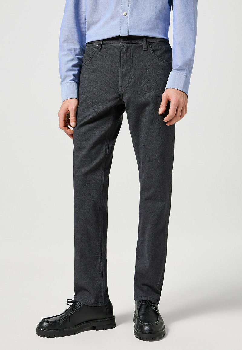 Donkergrijze, rechte broek gemaakt van een gestructureerde stof met een gladde afwerking. Heeft klassieke vijf-pocket styling en riemlussen.