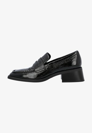 Mocassin en cuir noir brillant avec un bout carré et un petit talon bloc, présentant une couture style mocassin et une sangle sur le dessus.