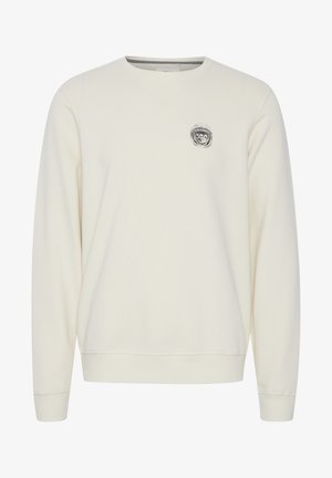 Kremna majica s dugimi rokavi, z rebrastimi manšetami in ovratnikom. Imenuje se majica, na prsih pa je majhna črna grafika. Mehka tekstura tkanine.