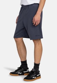 Navy blue sweat shorts with an elastic waistband and logo detail, made of soft fabric, featuring a relaxed fit and side pockets.
