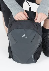 Czarny plecak o eleganckim designie, z fakturowaną tkaniną, przednią kieszenią na zamek, bocznymi kieszeniami siateczkowymi i białym logo z przodu.