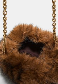 Braune Kunstfell-Handtasche mit einer weichen, strukturierten Außenseite, goldener Kettenhenkel und einem dunkel gefütterten Innenleben, das am Öffnungsrand sichtbar ist.