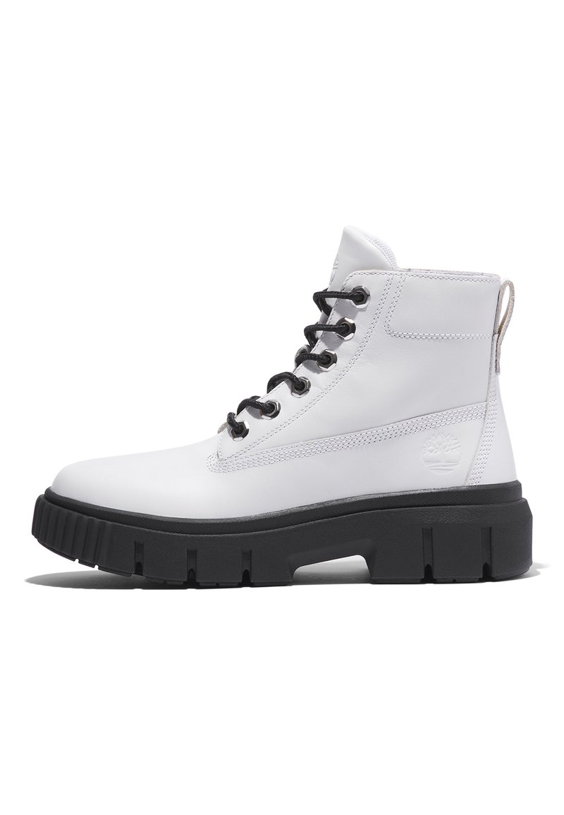 Bottes de cheville en cuir blanc avec lacets noirs, semelle épaisse noire, coutures contrastantes et une languette au talon arborant un logo.