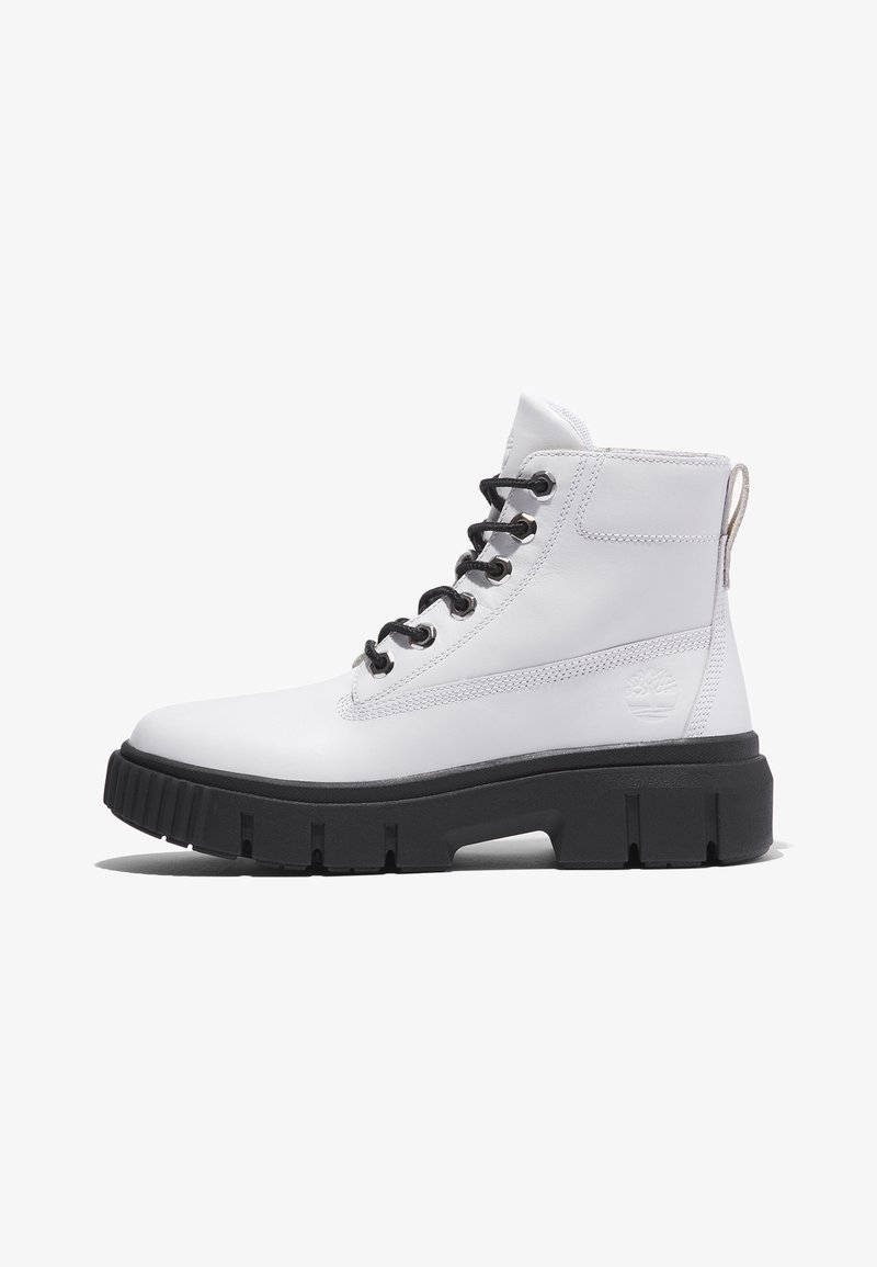Bottes de cheville en cuir blanc avec lacets noirs, semelle épaisse noire, coutures contrastantes et une languette au talon arborant un logo.