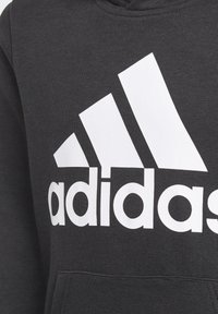 Czarna bluza z kapturem z białym logo "adidas" i trzema ukośnymi paskami. Materiał wygląda na miękki o gładkiej teksturze. Z przodu znajduje się kieszeń.
