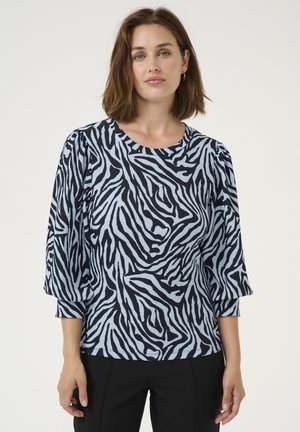 Haut rayé bleu et noir avec des manches trois-quarts, texture côtelée et encolure ronde, associé à un pantalon noir.