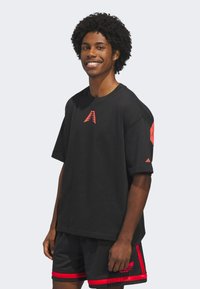 Black short-sleeve t-shirt with a red logo on the chest and red accents on sleeves, paired with black shorts featuring red stripes.
