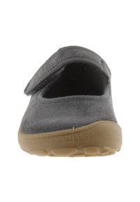 Zapato de ante gris con punta redonda y cierre de correa ajustable. Suela de goma texturizada en color marrón claro con patrones de agarre visibles.