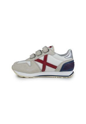Zapatilla deportiva blanca con acentos de piel de nobuk gris, patrón de cruces rojas y detalles azules en el talón. Cuenta con tres correas ajustables de Velcro.