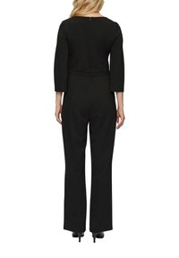 Zwarte jumpsuit met drie kwart mouwen, getailleerde taille en wijde pijpen, met een ritssluiting aan de achterkant en een gladde textuur.